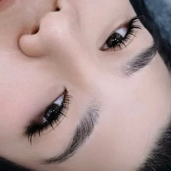 Close-up of a person's eyes with long, dark eyelashes and well-groomed eyebrows.