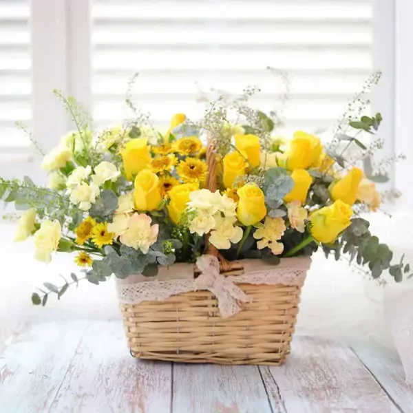 Basket of yellow roses, sunflowers, and carnations with eucalyptus greenery.
