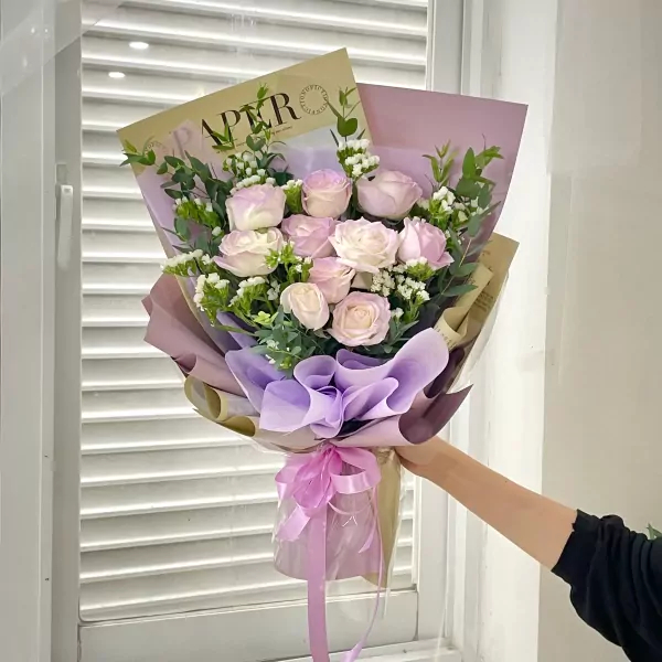 Bouquet of pink and white roses with eucalyptus and lavender wrapping, tied with a pink ribbon.