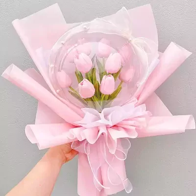Pink tulip bouquet in a clear bubble balloon with a sheer pink ribbon bow.
