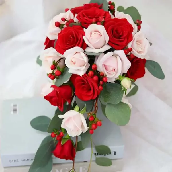 Cascade bouquet of red and cream roses with red berries and eucalyptus.
