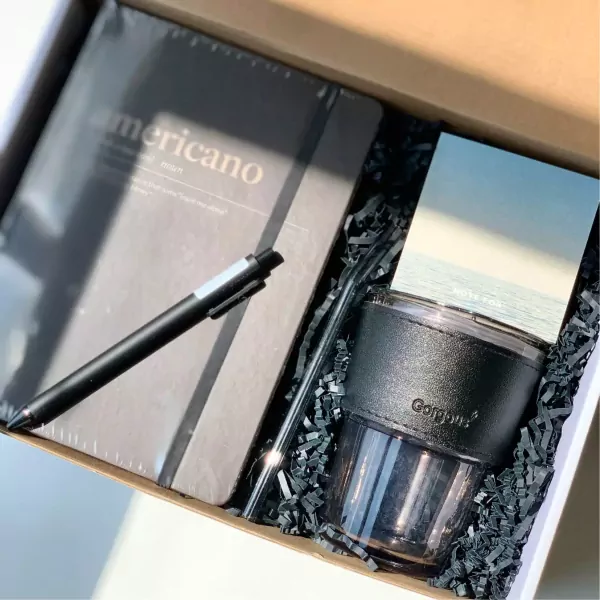 Gift set with notebook, pen, tumbler, and straw, "Americano" text visible.