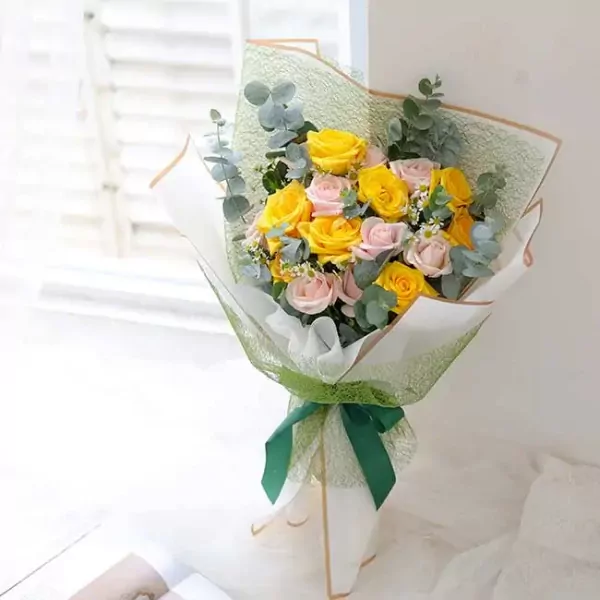 Bouquet of yellow and pink roses with eucalyptus and small white flowers.