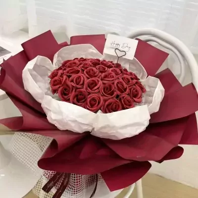 Red blooming bouquet with many red roses, white and red wrapping paper, and a "Happy Day" card.