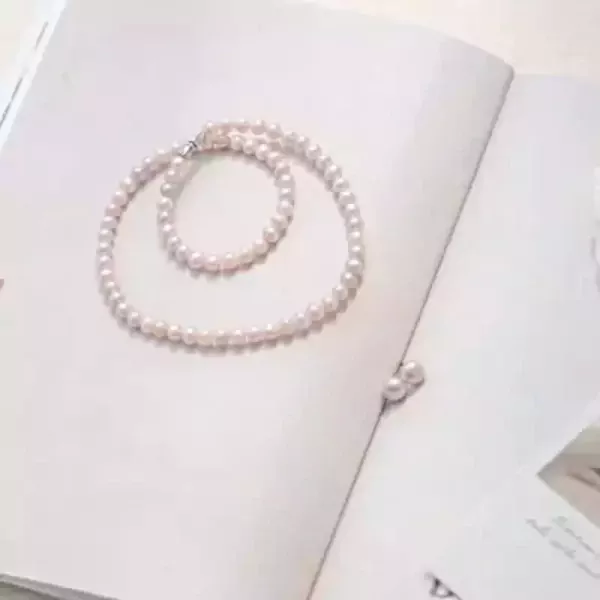 Pearl necklace on an open book with two loose pearls nearby.