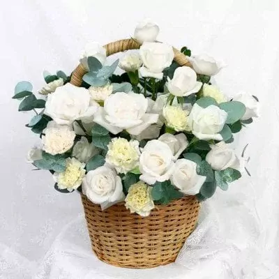 Basket of white roses, carnations, and greenery.