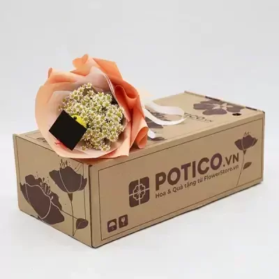 A bouquet of small white flowers wrapped in peach paper sits atop a cardboard box with "POTICO.VN" printed on it.