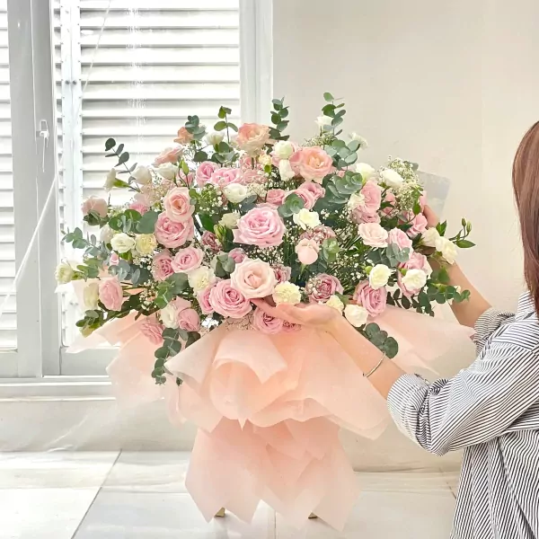 Large pink and white rose bouquet with eucalyptus, wrapped in pale pink tissue paper.