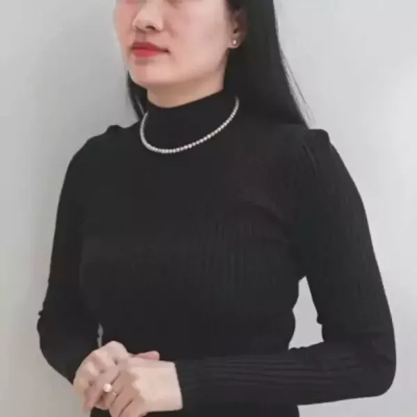 Woman in black turtleneck wearing a pearl necklace and a pearl ring.