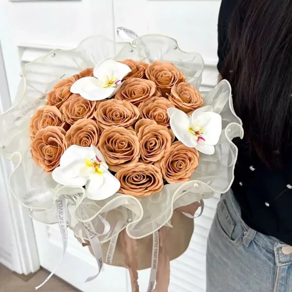 Peach roses with white orchids in a sheer, ruffled wrap.