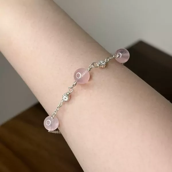 Silver bracelet with pink beads and clear accent stones on a person's arm.