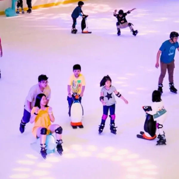 People ice skating at Vincom Landmark 81, with children using penguin helpers.