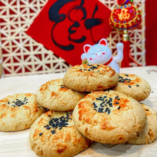 A stack of sesame seed cookies with a lucky cat figurine in the background.