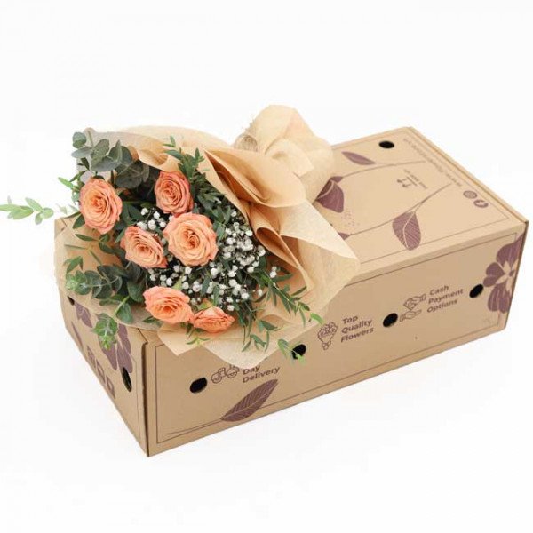 Boxed bouquet of peach roses and baby's breath with eucalyptus leaves.