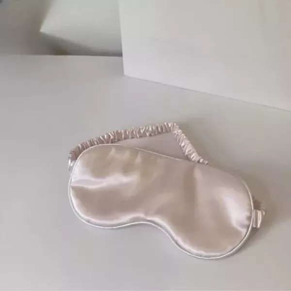 Silk sleep mask with elastic strap on a white surface.
