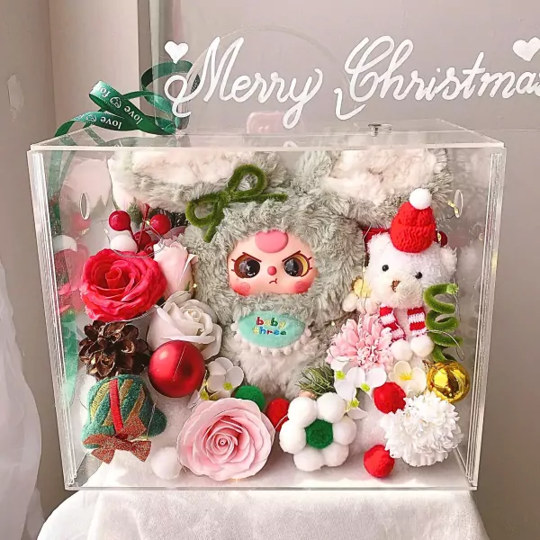 Clear box filled with plush toys, flowers, and Christmas decorations.
