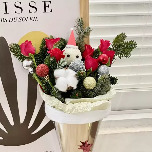Christmas bouquet with red roses, pine branches, festive ornaments, and a snowman figure.