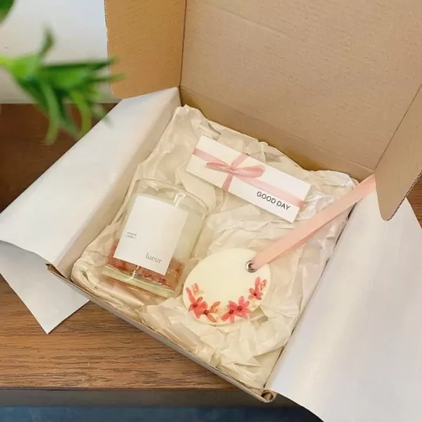 Gift box with scented candle, "Good Day" card, and floral wax ornament.