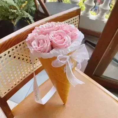 Pink roses in a waffle cone arrangement with a white ribbon.