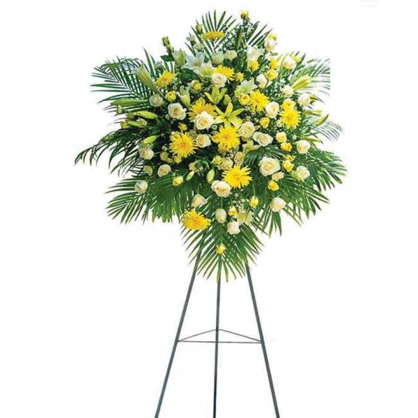 Funeral flower stand with yellow lilies, chrysanthemums, and roses.