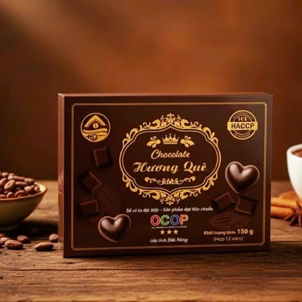 Brown box of Le Chocolatier chocolate with heart-shaped chocolates and cocoa beans.