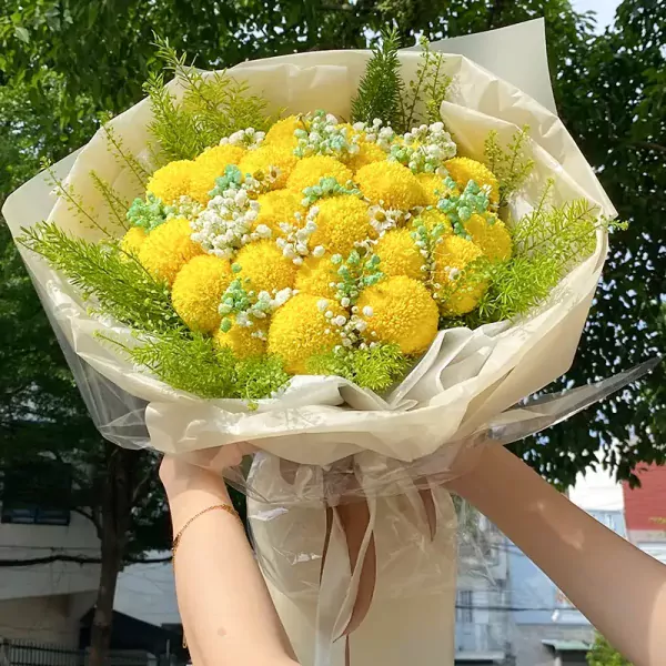 A bouquet of yellow ping pong chrysanthemums, baby's breath, and greenery.