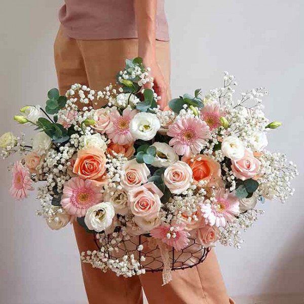 Basket of pink and peach roses, gerbera daisies, and baby's breath.