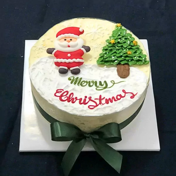 Christmas cake with Santa, tree, "Merry Christmas" text, and green ribbon.