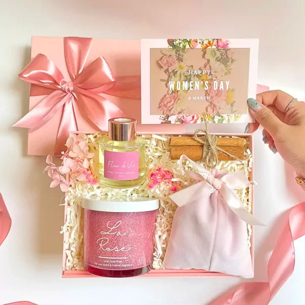 Pink gift box with La Rose candle, diffuser, LOVE bag, cinnamon sticks, and Women's Day card.