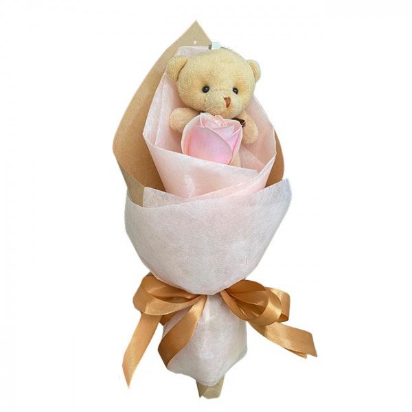 Cute teddy bear and pink rose in a gift bouquet, tied with a gold ribbon.