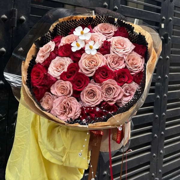 Bouquet of red and pink roses with white flowers and decorative beads.