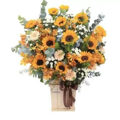 Basket of sunflowers, gerbera daisies, and eucalyptus in a wooden box with a brown ribbon.