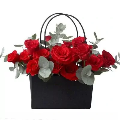 Black flower bag with vibrant red roses and greenery.