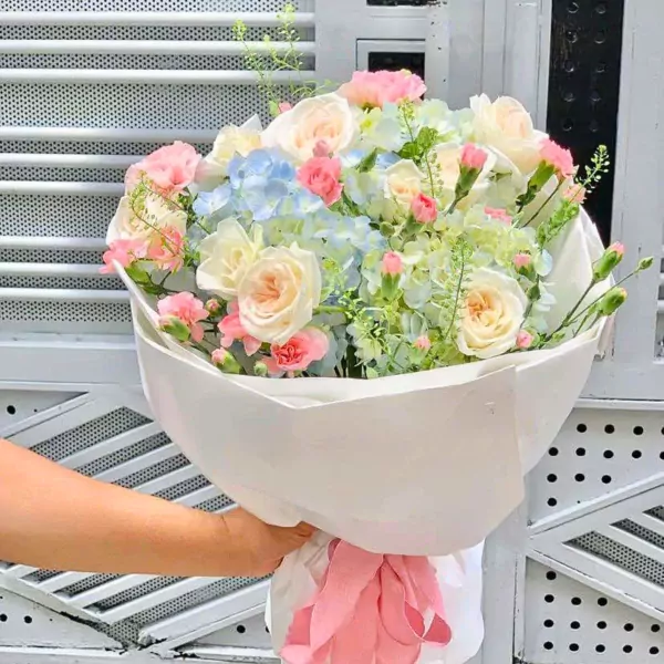 Bouquet of pink and white roses, blue hydrangeas, and pink carnations.