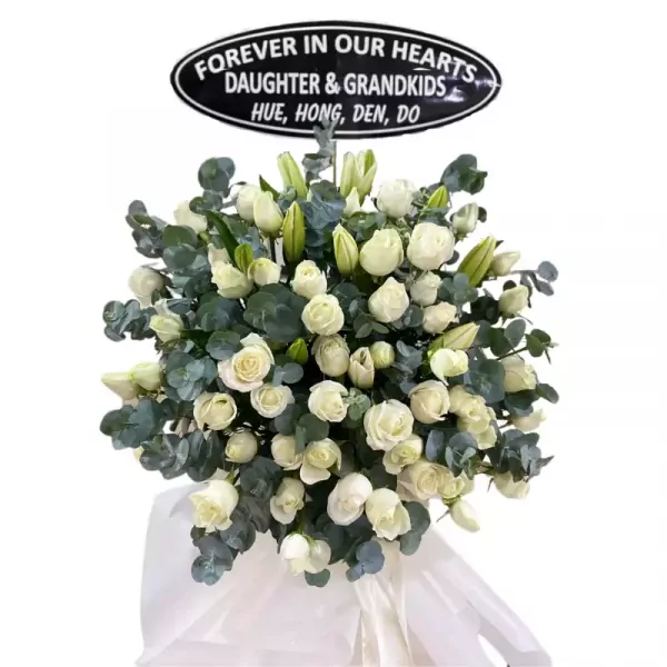 White roses and lilies funeral wreath with a memorial plaque.