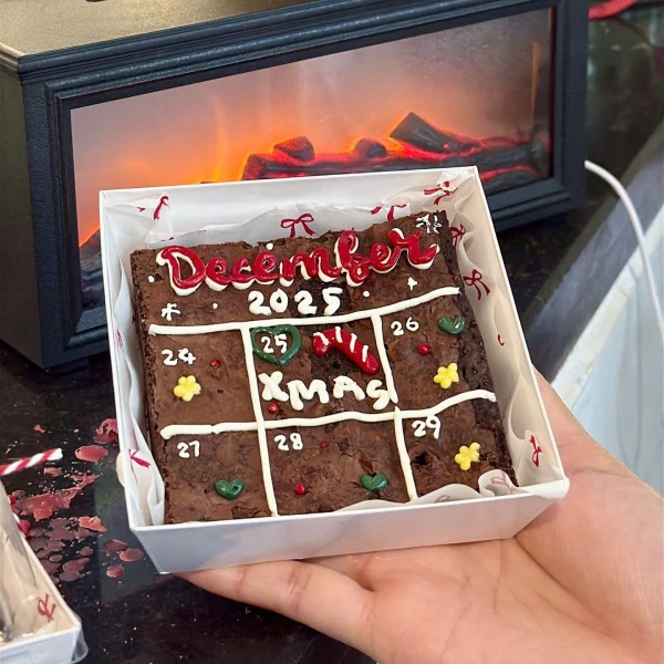 Christmas brownie calendar with "December 2025" and "Xmas" decorated with festive icing.