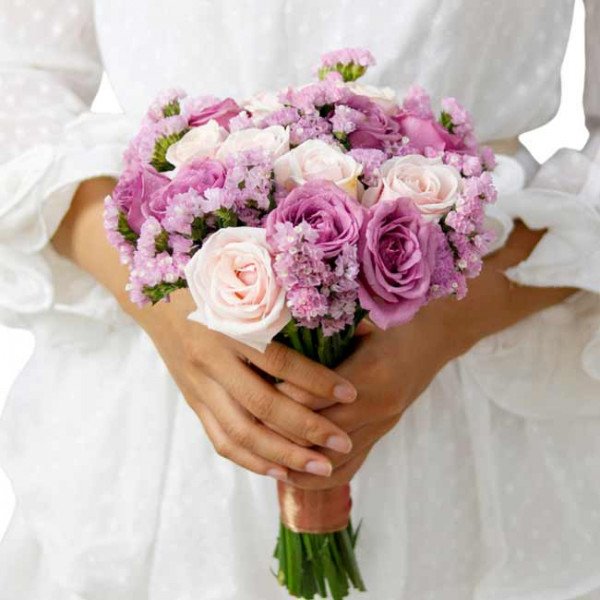 Bridal bouquet of purple and cream roses with purple statice.