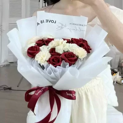 Red scarlet bouquet with white accents, wrapped in white paper and tied with a red ribbon.