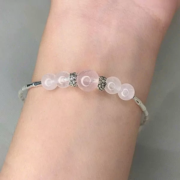 Ethereal Bloom bracelet with rose quartz and silver charms on a wrist.