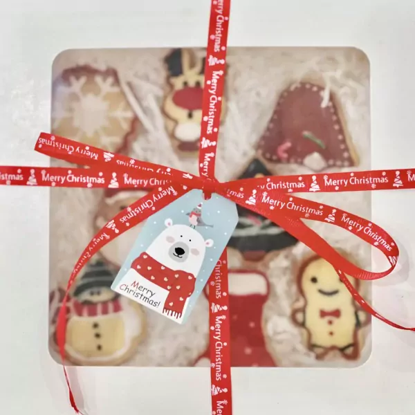 Christmas cookies in gift box with red ribbon and polar bear tag.