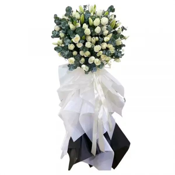 Funeral wreath with white roses, lilies, and eucalyptus.