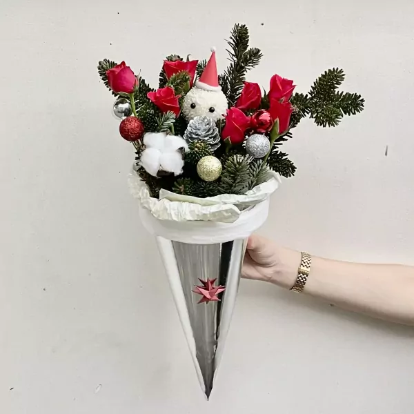 Christmas bouquet in a silver cone with red roses, pine branches, and a snowman decoration.