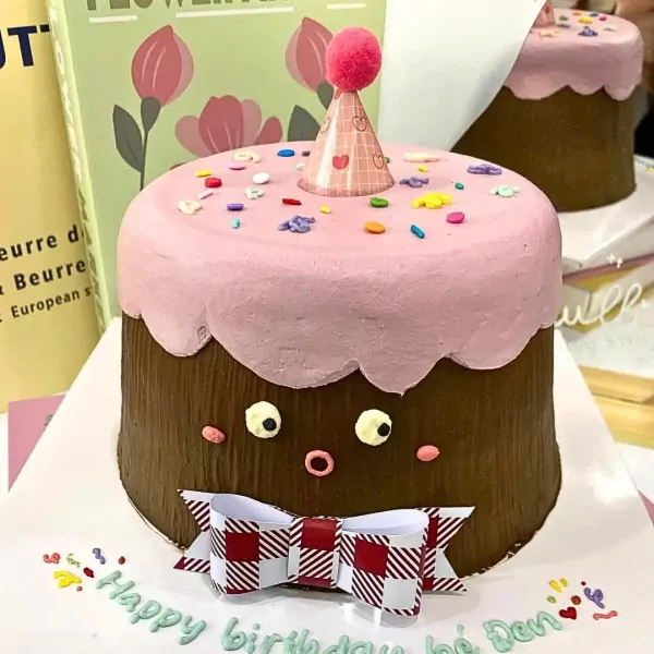 Cute chocolate cake with pink frosting, rosy cheeks, and a bow tie.