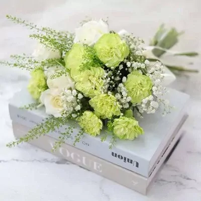 White roses and green carnations with baby's breath in a bridal bouquet.