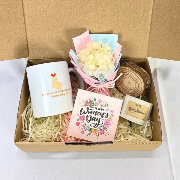 Women's Day gift box with mug, dried flowers, candle, and wooden coaster.