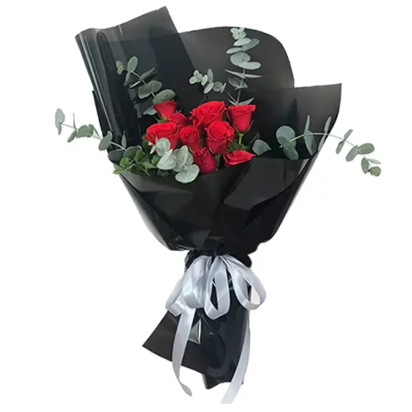 Red roses wrapped in black paper with eucalyptus and a silver ribbon.