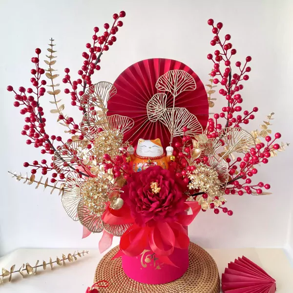Maneki-neko cat with red berries, gold leaves, and a red peony in a pink box.