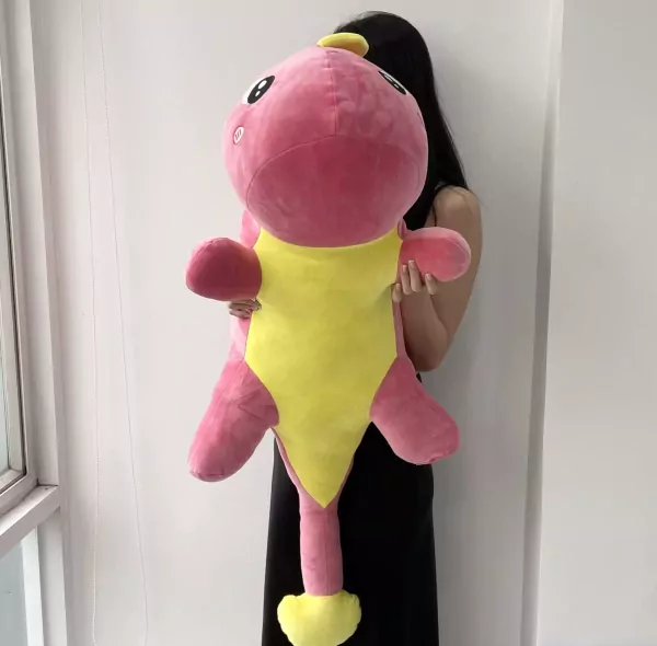 A person holds a large pink and yellow plush dinosaur toy.