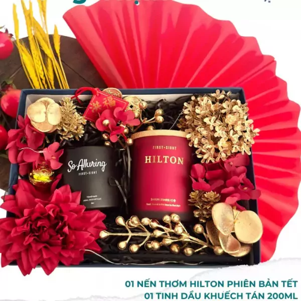 Gift box with two scented candles, red floral accents, and gold decorations.