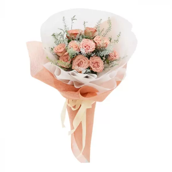Bouquet of pink cappuccino roses wrapped in peach and white paper with a cream ribbon.